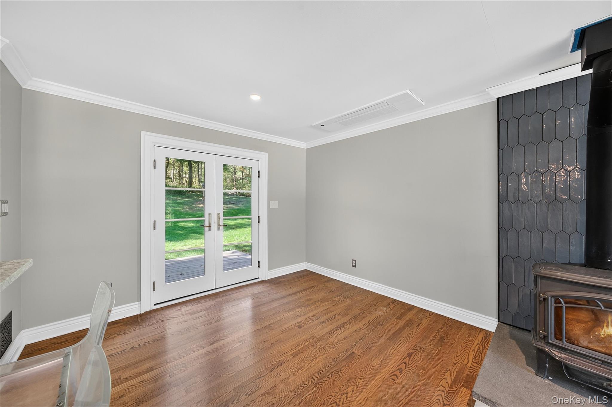 65 Hawxhurst Road Monroe, NY 10950 - Photo 13 of 35 Unfurnished living room with crown molding, french doors, a wood stove, wood finished floors, and recessed lighting