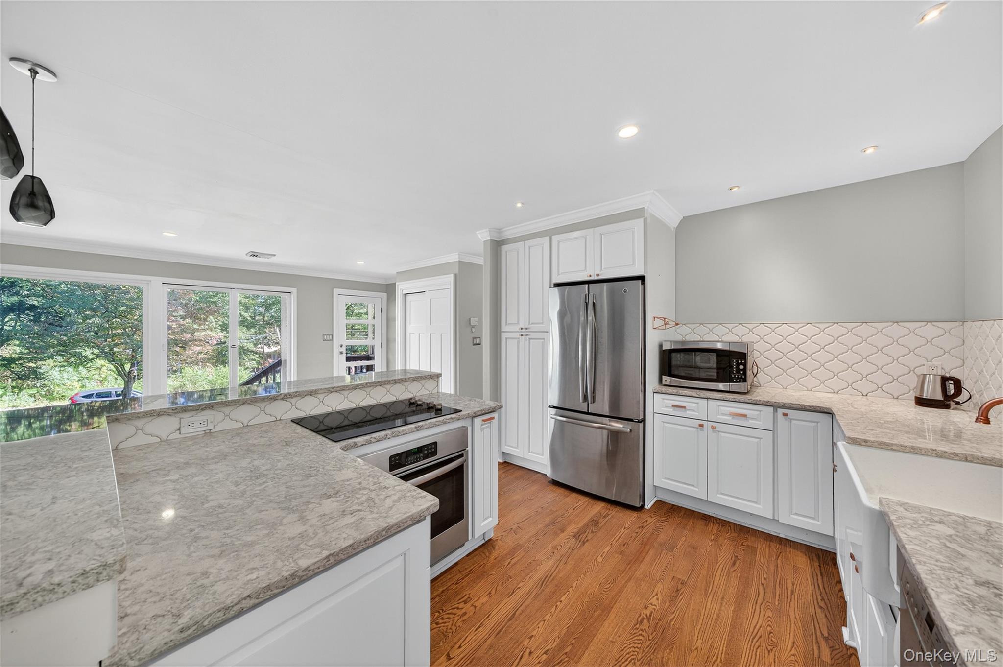65 Hawxhurst Road Monroe, NY 10950 - Photo 15 of 35 Kitchen featuring appliances with stainless steel finishes, light stone counters, backsplash, white cabinetry, and light wood finished floors