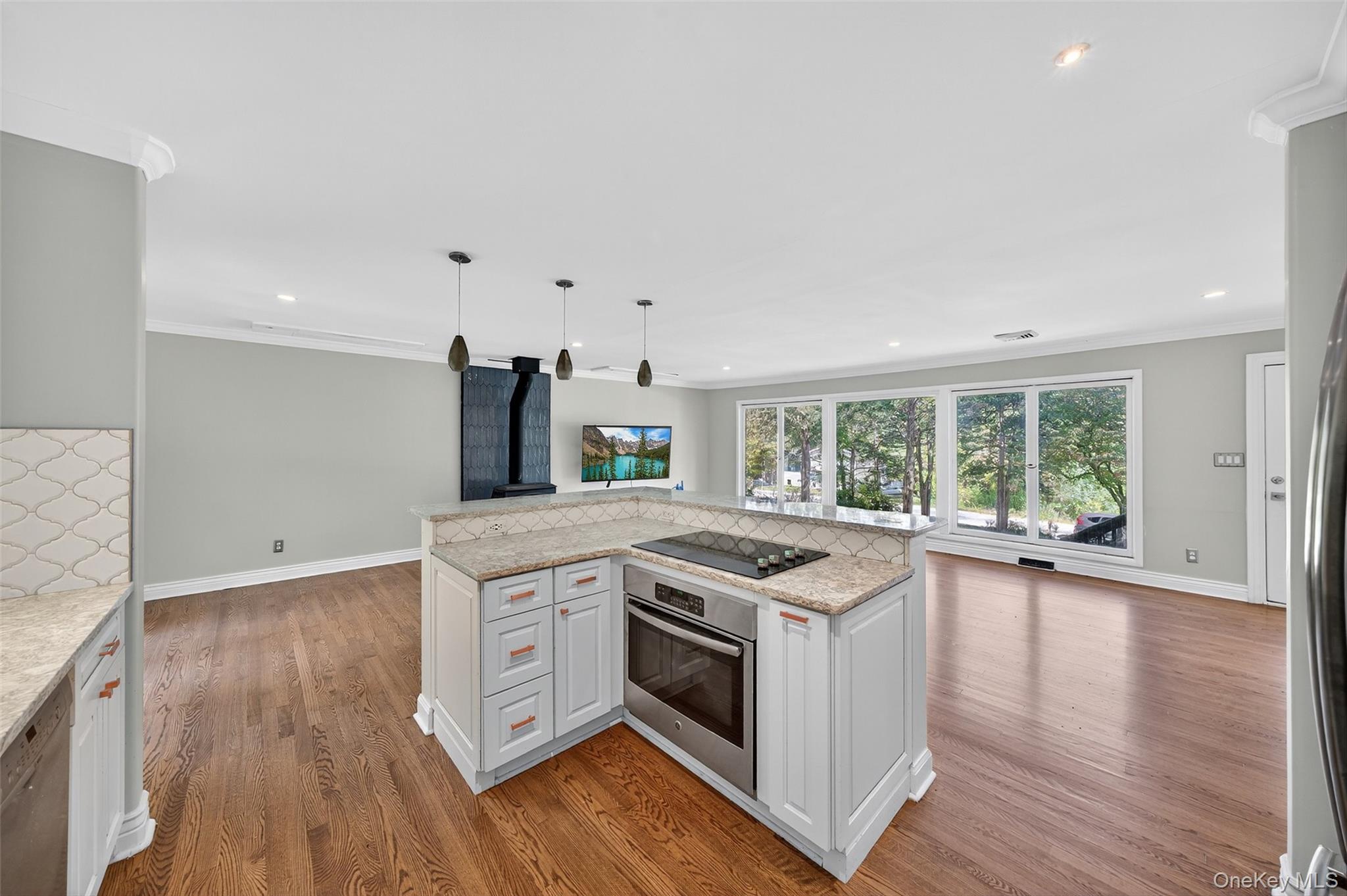 65 Hawxhurst Road Monroe, NY 10950 - Photo 35 of 35 Kitchen featuring light stone countertops, stainless steel appliances, white cabinetry, open floor plan, and crown molding