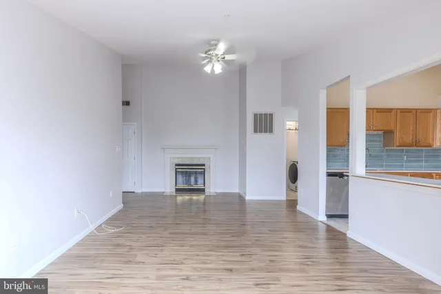 a view of an empty room with wooden floor and a fireplace