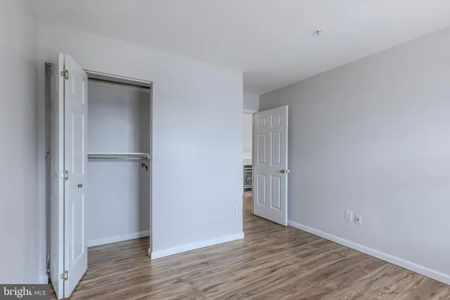 a view of an empty room with wooden floor & closet