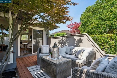a view of a patio with couches table and chairs with wooden floor and fence