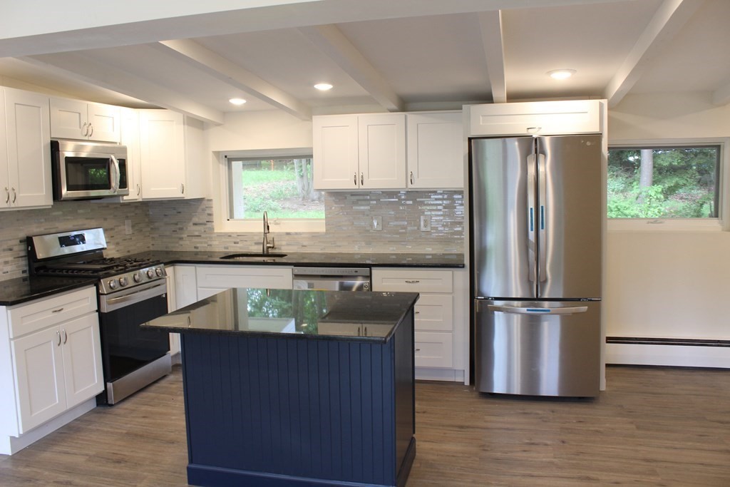 a kitchen with granite countertop a refrigerator stove top oven and sink