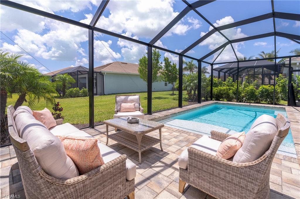 14488 Stillwater Way Naples, FL 34114 - Photo 13 of 36 Swimming pool featuring a sunroom, a lawn, and a patio area