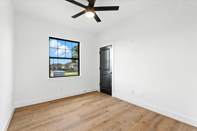 a view of empty room with wooden floor and window