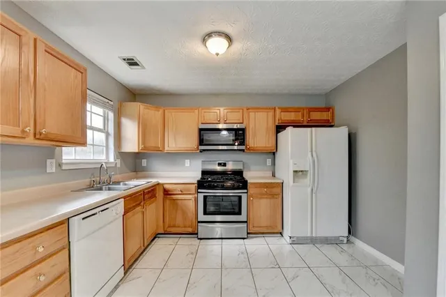 a kitchen with stainless steel appliances granite countertop a stove a sink and a refrigerator