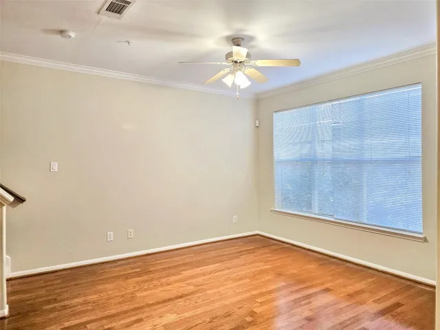 an empty room with wooden floor fan and windows