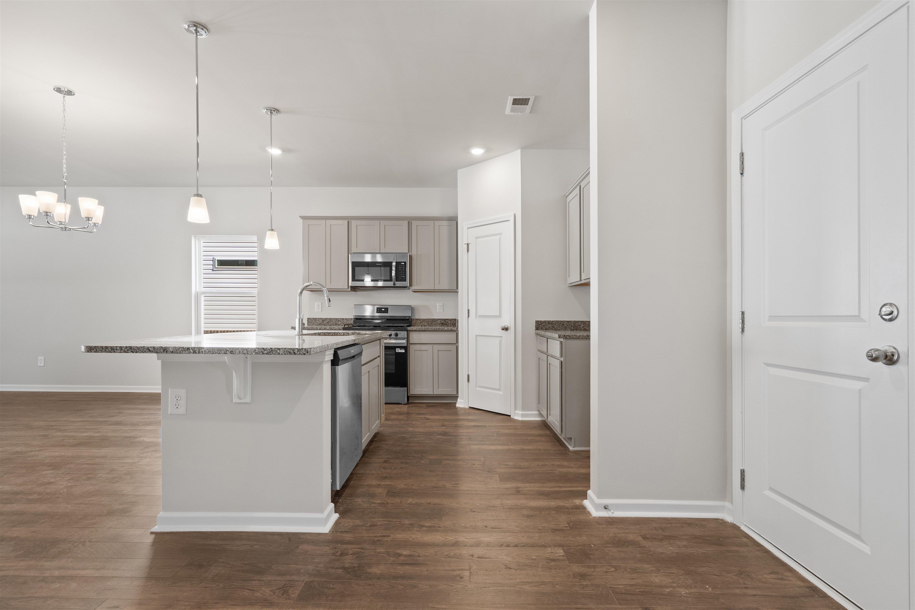 2491 Campton Loop Conway, SC 29527 - Photo 11 of 38 Kitchen featuring appliances with stainless steel finishes, dark wood-style floors, pendant lighting, a center island with sink, and a breakfast bar area