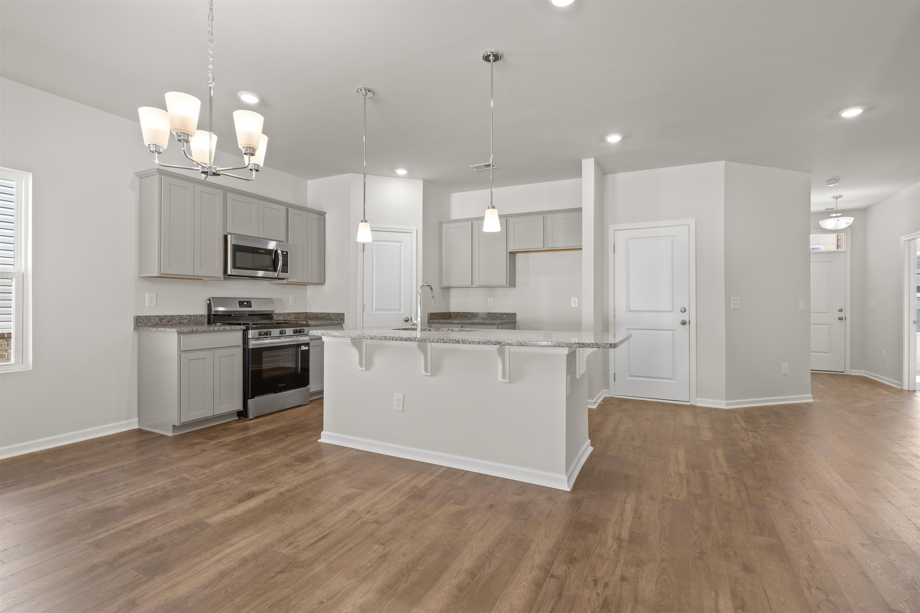 2491 Campton Loop Conway, SC 29527 - Photo 9 of 38 Kitchen featuring appliances with stainless steel finishes, a breakfast bar area, light stone counters, a chandelier, and pendant lighting