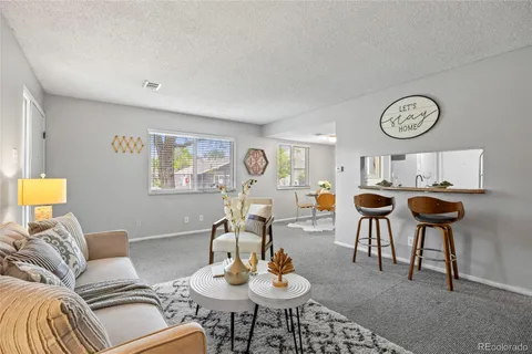 a living room with furniture a clock and a view of kitchen