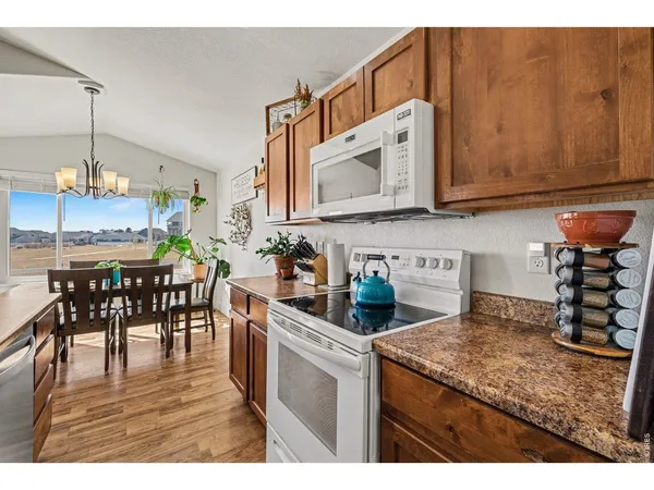 a kitchen with stainless steel appliances granite countertop a stove top oven a sink a dining table and chairs