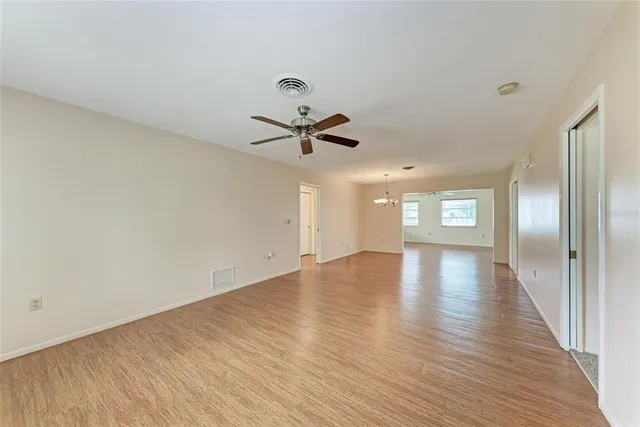 a view of empty room with wooden floor and ceiling fan