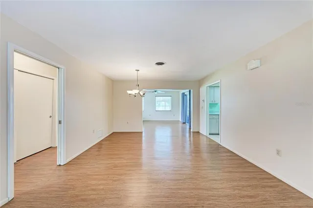 a view of an empty room with window and wooden floor