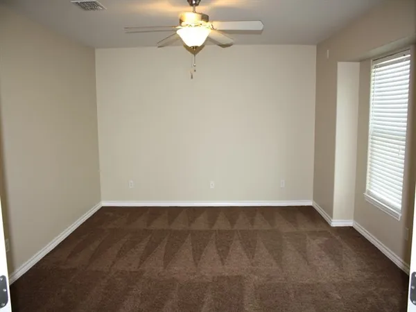 an empty room with a chandelier fan and windows