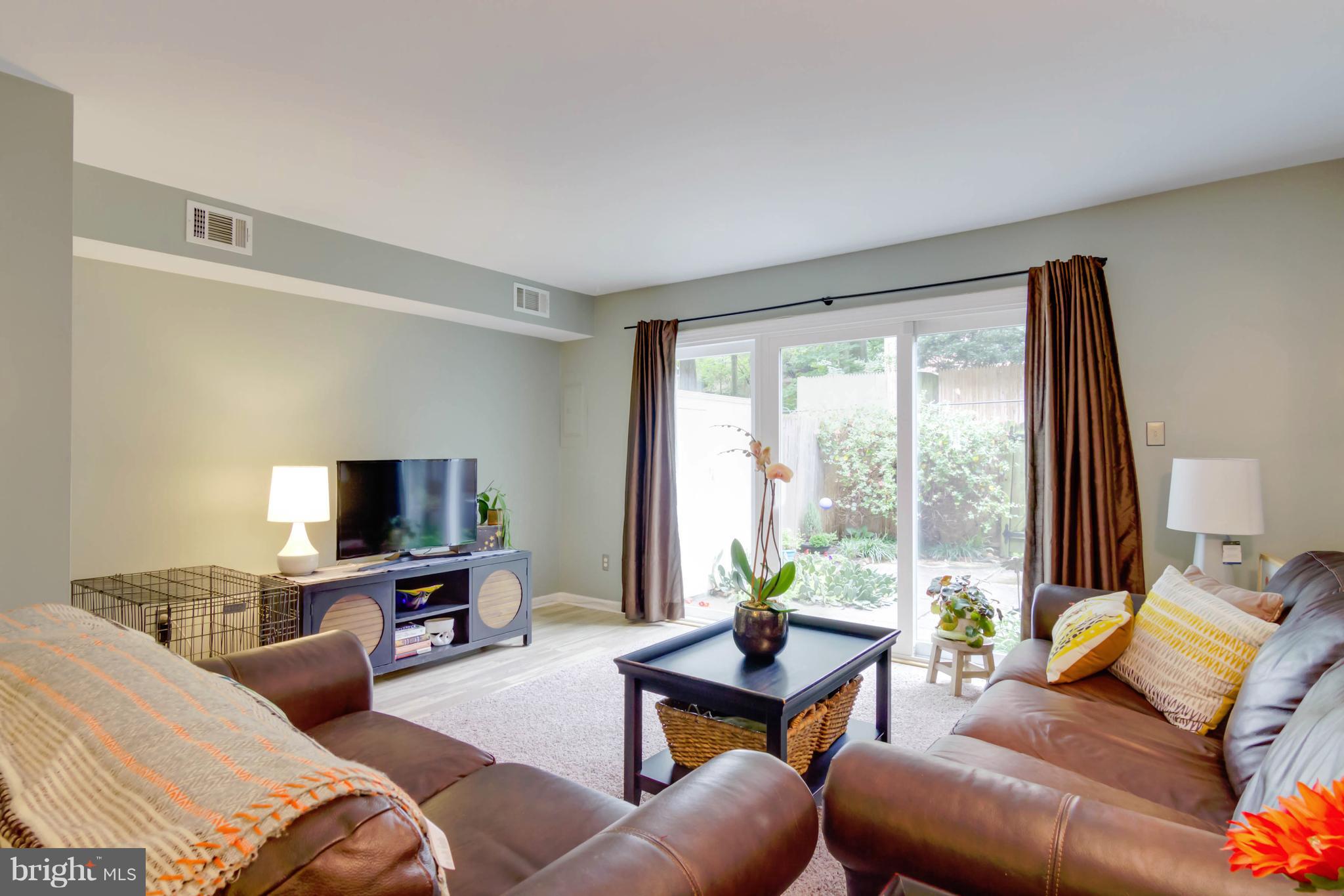 8317 Kingsgate Road, Unit 517 Springfield, VA 22152 - Photo 6 of 30 a living room with furniture a flat screen tv and a floor to ceiling window