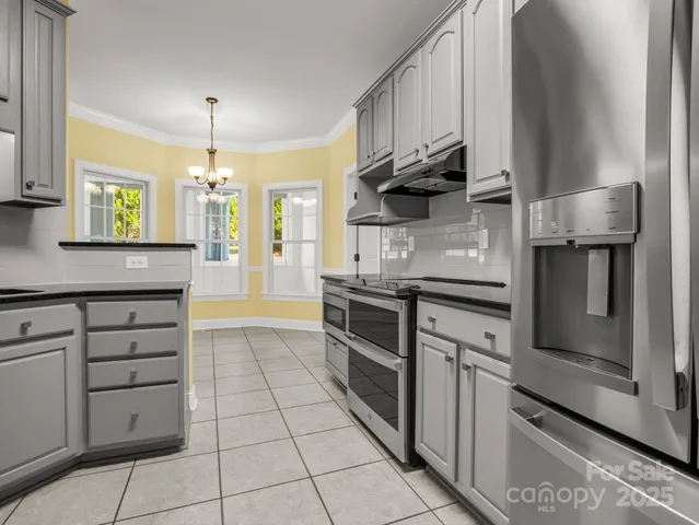 a kitchen with granite countertop a stove cabinets and stainless steel appliances