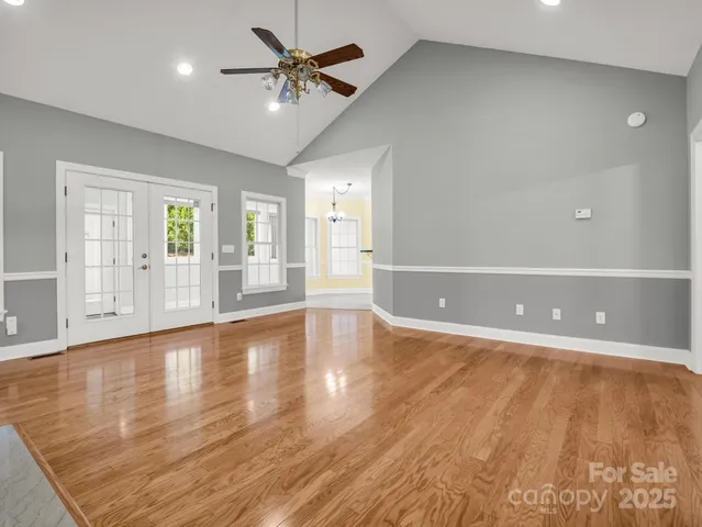 a view of an empty room with window and wooden floor