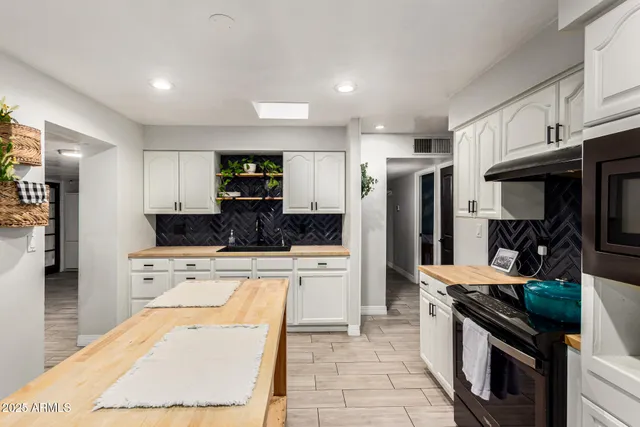 a kitchen with stainless steel appliances kitchen island granite countertop a refrigerator oven a sink dishwasher and white cabinets with wooden floor