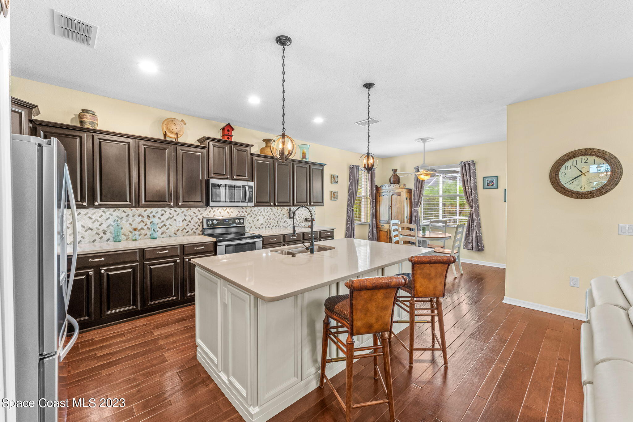 3428 Ahern Place Melbourne, FL 32940 - Photo 24 of 64 a kitchen with stainless steel appliances granite countertop a stove top oven a sink island a dining table and chairs with wooden floor