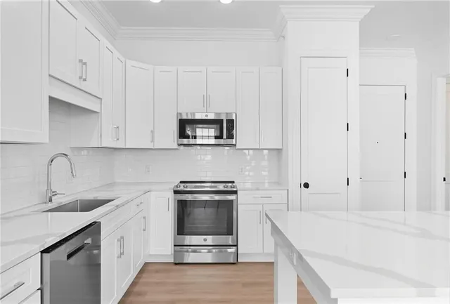 a kitchen with stainless steel appliances granite countertop a stove a sink and a microwave