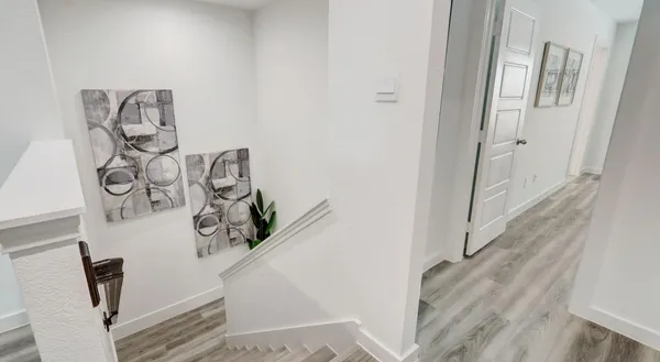 a view of a hallway with white walls and wooden floor