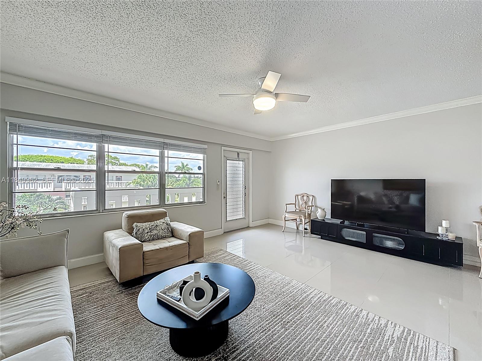 618 Fanshaw O, Unit 618 Boca Raton, FL 33434 - Photo 11 of 40 a living room with furniture a flat screen tv and a large window