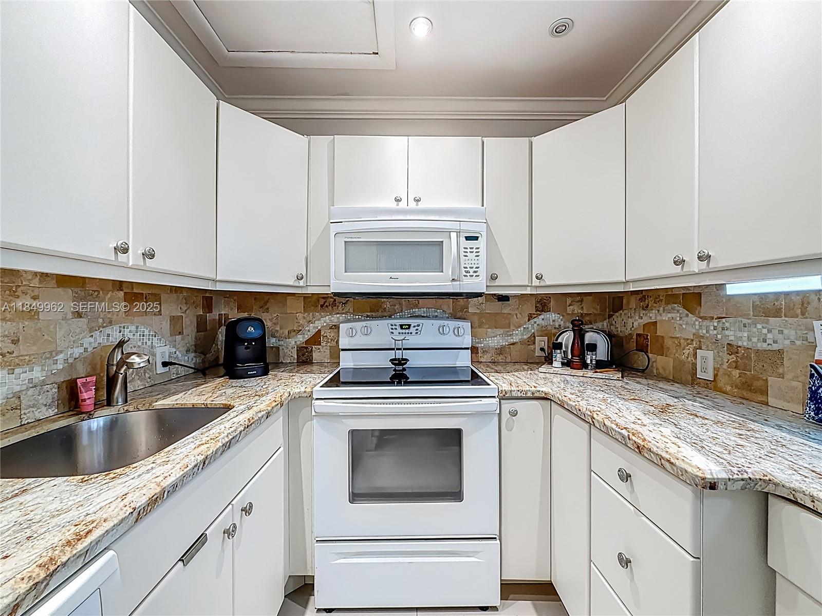 618 Fanshaw O, Unit 618 Boca Raton, FL 33434 - Photo 17 of 40 a kitchen with granite countertop white cabinets and white appliances