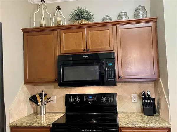 a kitchen with granite countertop stove top oven and cabinets