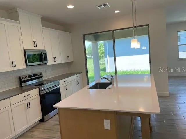 a kitchen with a sink a stove top oven and white cabinets