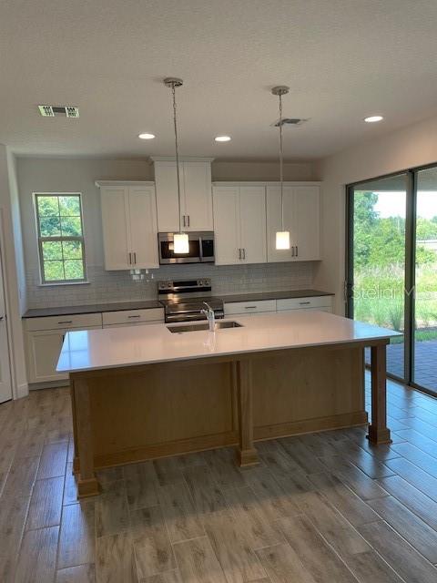 7501 Wing Span Way Harmony, FL 34773 - Photo 6 of 30 a view of kitchen with kitchen island a sink wooden floor and a window
