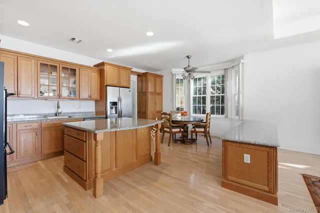 a kitchen with stainless steel appliances granite countertop a stove top oven a sink dishwasher and a refrigerator with wooden floor