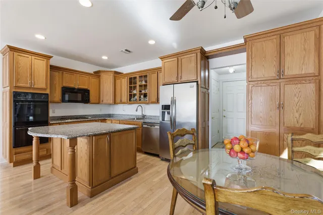 a kitchen with stainless steel appliances granite countertop a refrigerator a stove a sink cabinets and a dining table