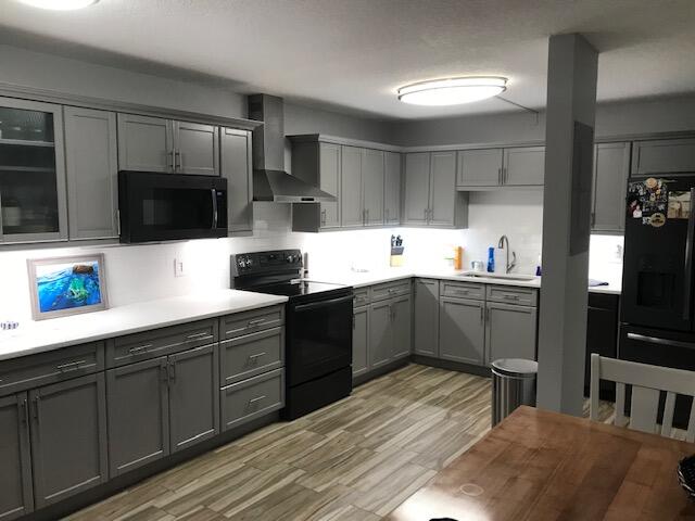 825 Center Street, Unit 1B Jupiter, FL 33458 - Photo 4 of 16 a kitchen with stainless steel appliances a sink dishwasher a microwave oven a stove with white cabinets and wooden floor