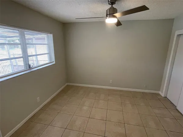 an empty room with windows and fan