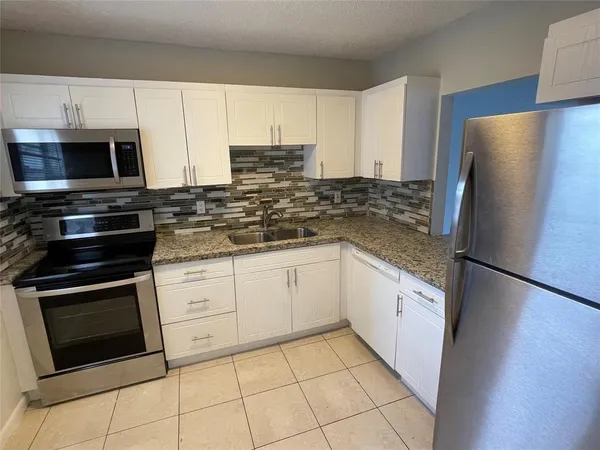 a kitchen with stainless steel appliances granite countertop a refrigerator stove a sink and a microwave