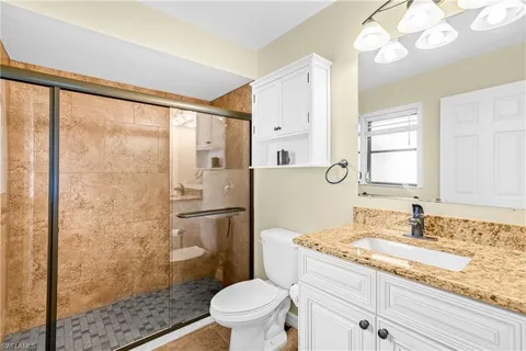 a bathroom with a granite countertop sink toilet and shower