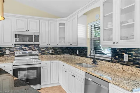 a kitchen with granite countertop a sink a stove and cabinets