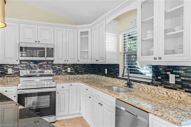 a kitchen with granite countertop a sink a stove and cabinets