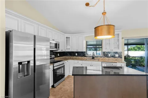 a kitchen with stainless steel appliances a refrigerator a sink a stove and white cabinets