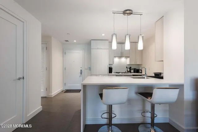 a view of a kitchen with a sink a refrigerator and chairs