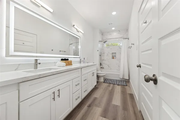 a spacious bathroom with a double vanity sink mirror and shower