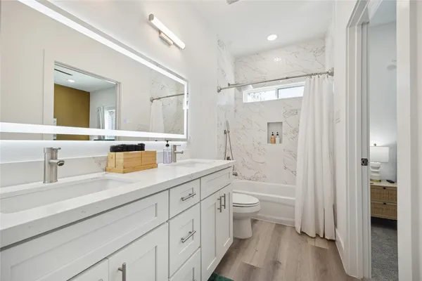 a bathroom with a double vanity sink toilet mirror and bathtub