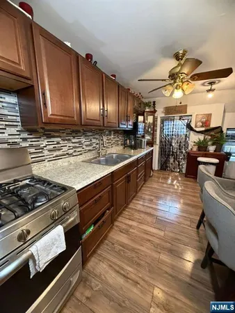 a kitchen with stainless steel appliances granite countertop a stove a sink dishwasher and cabinets with wooden floor