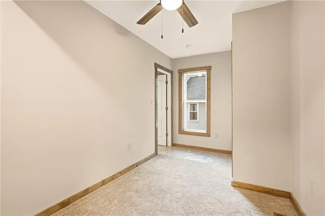 an empty room with chandelier fan and windows