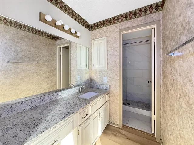 a bathroom with a granite countertop sink a mirror and a shower
