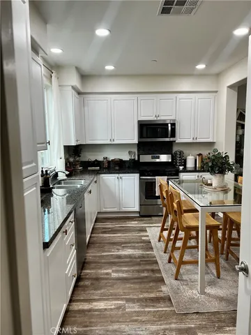 a kitchen with stainless steel appliances kitchen island granite countertop a stove top oven a sink a microwave and a refrigerator