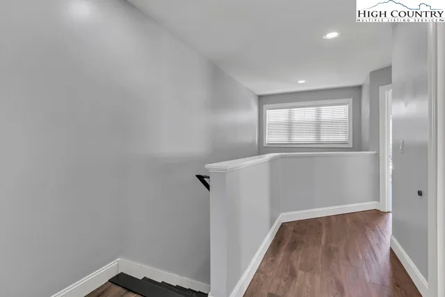 a view of hallway with window and wooden floor