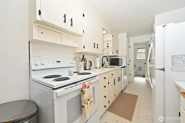 a kitchen with granite countertop a stove a sink and a refrigerator