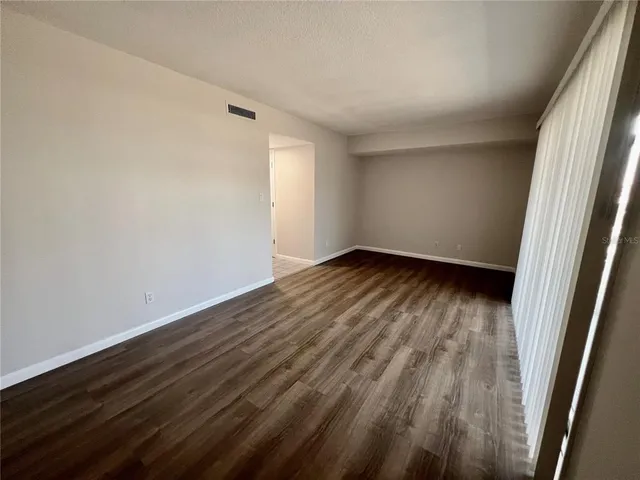 a view of an empty room with wooden floor and a window