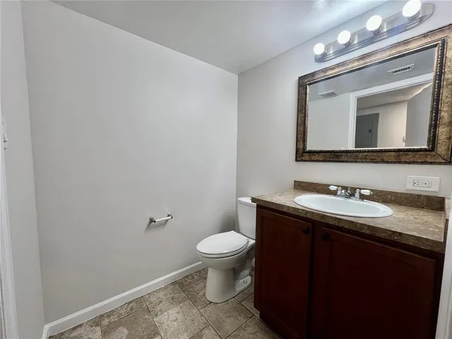 a bathroom with a granite countertop sink a toilet and a mirror